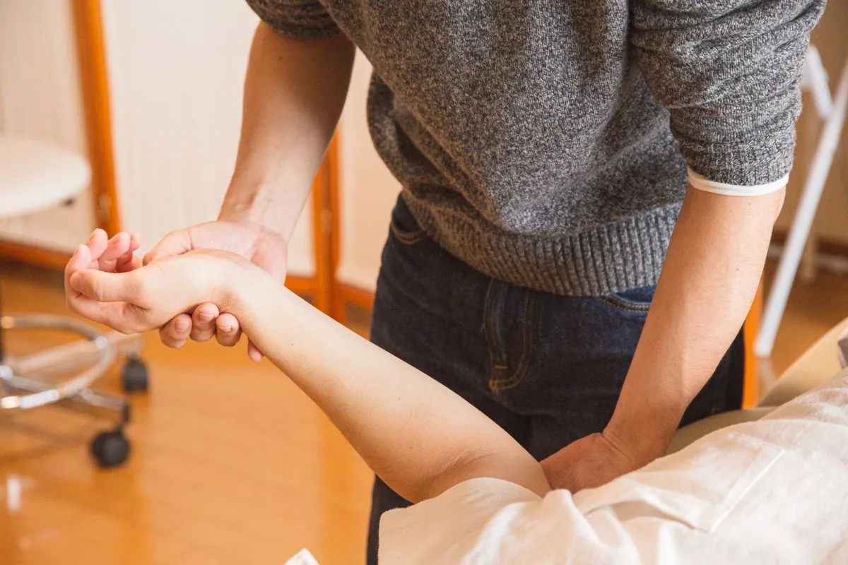 A therapist's hands examining a patient's wrist